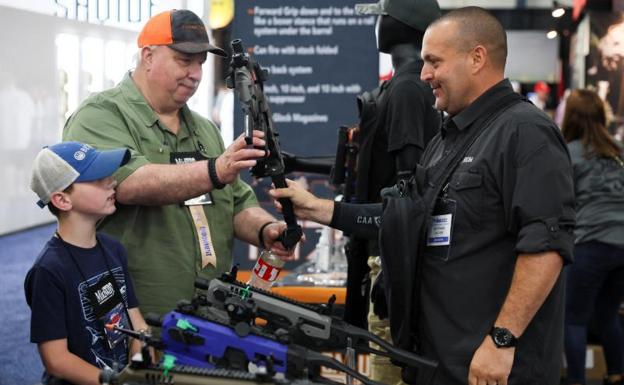 A man holds a pistol conversion kit next to a child during the convention that kicked off this Friday./REUTERS